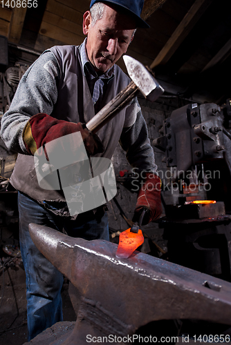 Image of blacksmith manually forging the molten metal