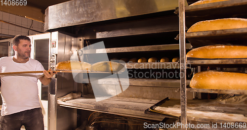 Image of bakery worker taking out freshly baked breads