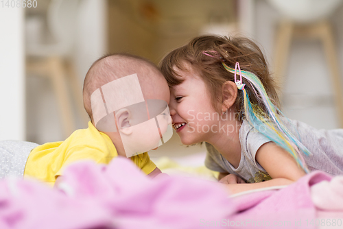 Image of little sister and her baby brother playing at home