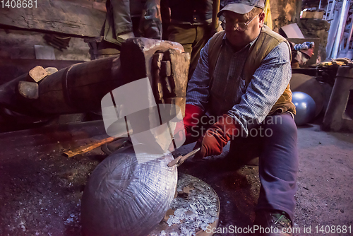 Image of blacksmith workers using mechanical hammer at workshop