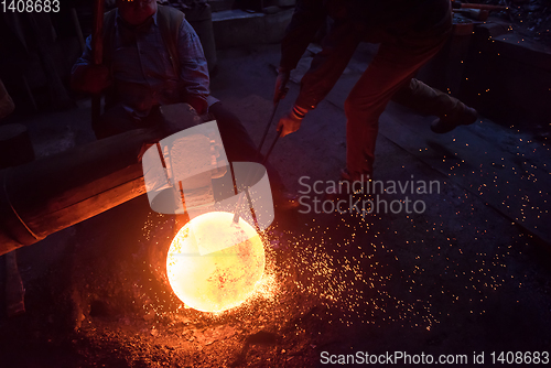 Image of blacksmith workers using mechanical hammer at workshop