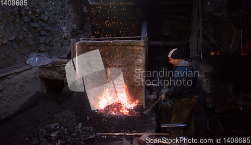 Image of young traditional Blacksmith working with open fire