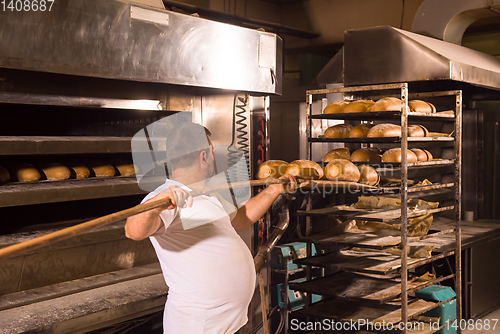 Image of bakery worker taking out freshly baked breads