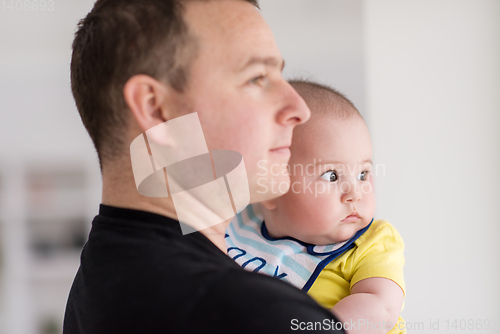Image of young father holding baby near the window at home
