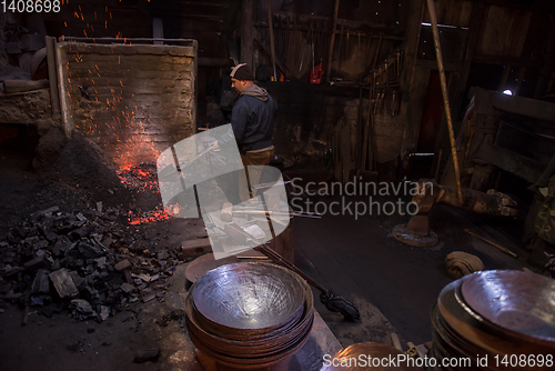 Image of young traditional Blacksmith working with open fire