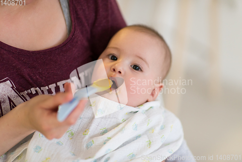 Image of mother with spoon feeding little baby