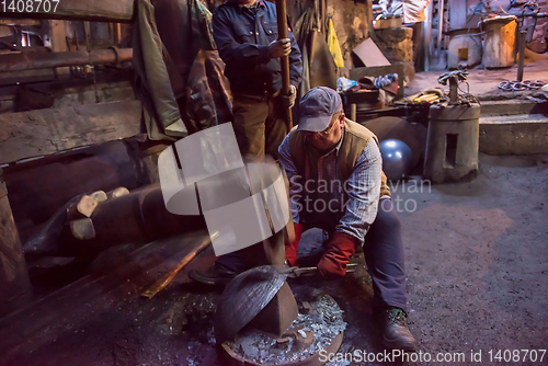 Image of blacksmith workers using mechanical hammer at workshop