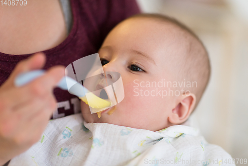 Image of mother with spoon feeding little baby