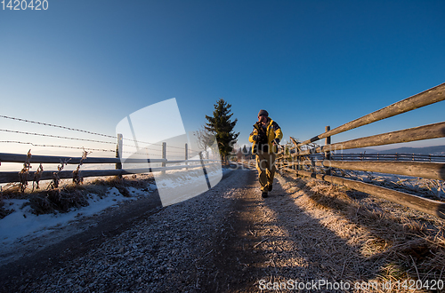 Image of young photographer walking on country road