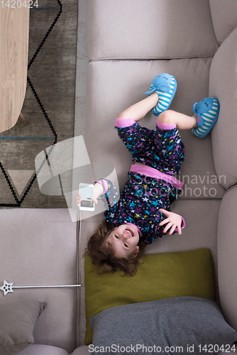 Image of top view of little girl using a smartphone on the sofa