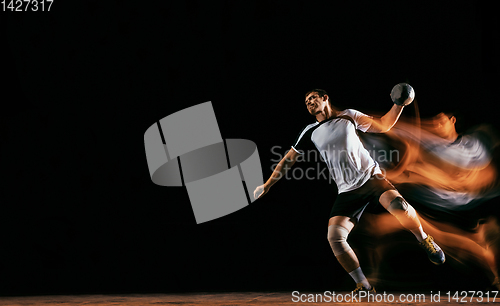 Image of Young handball player against dark studio background in mixed light