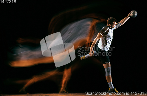 Image of Young handball player against dark studio background in mixed light