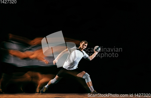 Image of Young handball player against dark studio background in mixed light