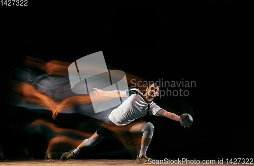 Image of Young handball player against dark studio background in mixed light