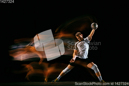 Image of Young handball player against dark studio background in mixed light