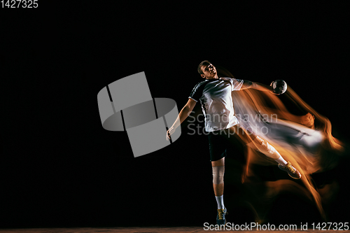 Image of Young handball player against dark studio background in mixed light