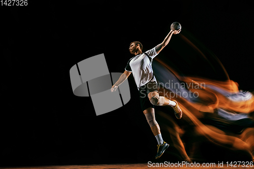 Image of Young handball player against dark studio background in mixed light