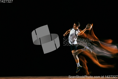 Image of Young handball player against dark studio background in mixed light