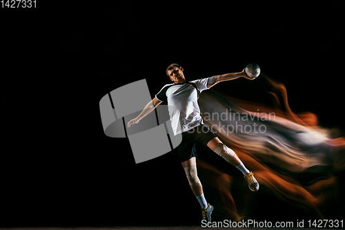 Image of Young handball player against dark studio background in mixed light