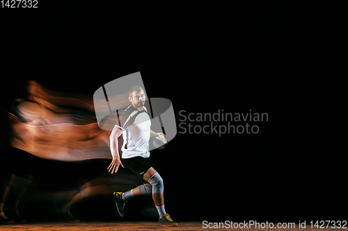 Image of Young handball player against dark studio background in mixed light