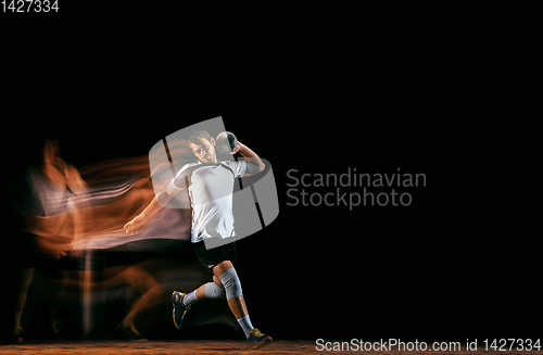 Image of Young handball player against dark studio background in mixed light