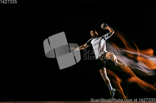 Image of Young handball player against dark studio background in mixed light