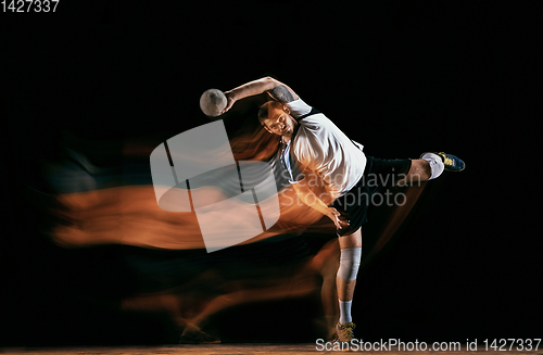 Image of Young handball player against dark studio background in mixed light