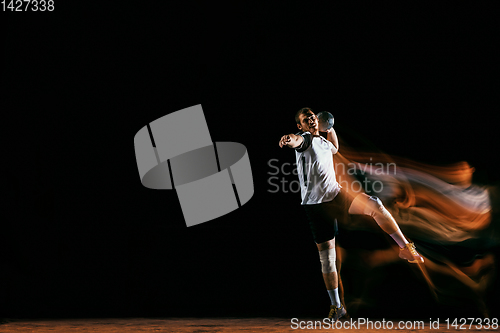 Image of Young handball player against dark studio background in mixed light