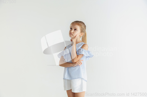 Image of Little smiling girl posing in casual clothes on white studio background