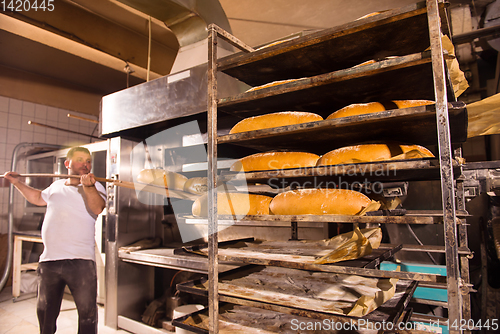 Image of bakery worker taking out freshly baked breads