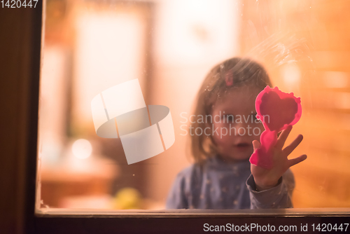 Image of little cute girl playing near the window