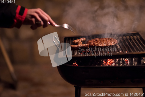 Image of young man cooking meat on barbecue