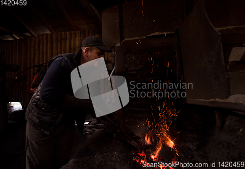 Image of young traditional Blacksmith working with open fire