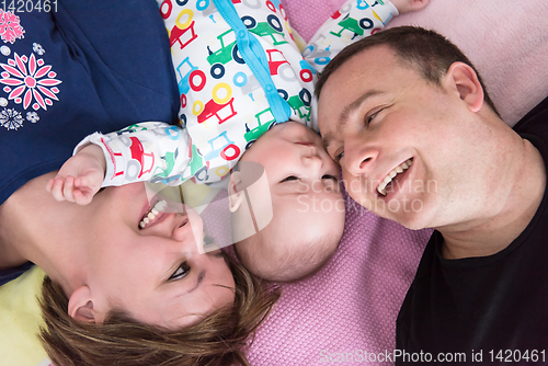 Image of Top view of smiling young couple lying with their baby