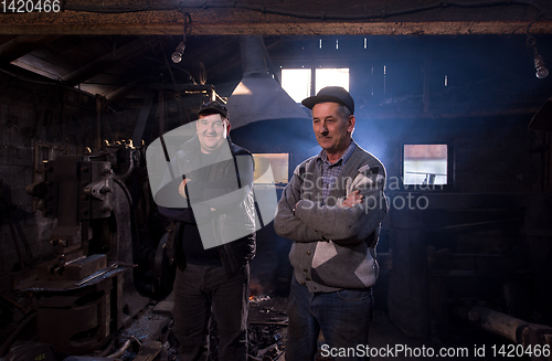 Image of portrait of two generations confident blacksmith