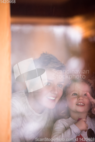 Image of young mother and little cute daughter playing near the window