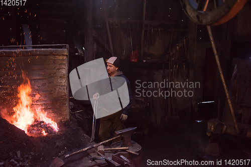 Image of young traditional Blacksmith working with open fire