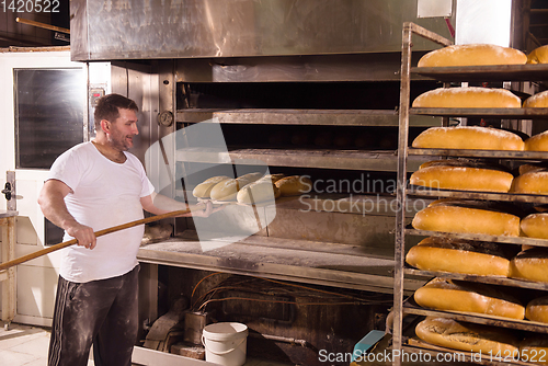 Image of bakery worker taking out freshly baked breads