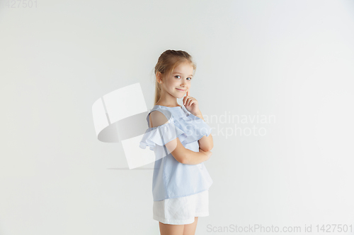 Image of Little smiling girl posing in casual clothes on white studio background