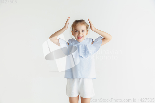 Image of Little smiling girl posing in casual clothes on white studio background