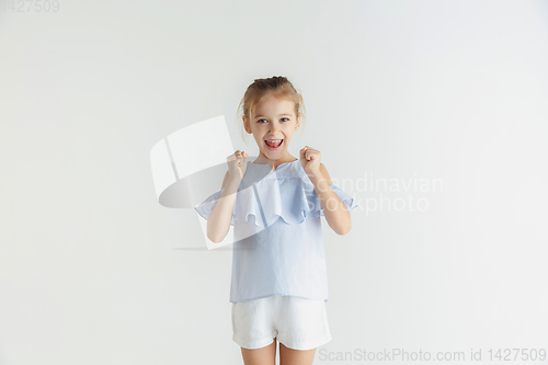 Image of Little smiling girl posing in casual clothes on white studio background