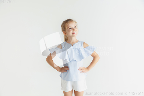 Image of Little smiling girl posing in casual clothes on white studio background