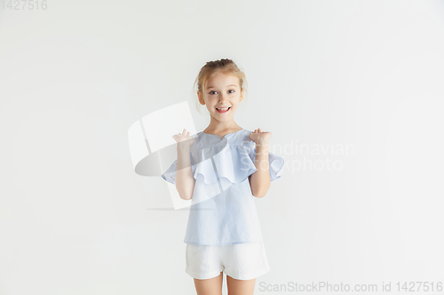 Image of Little smiling girl posing in casual clothes on white studio background