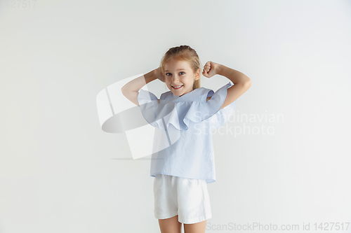 Image of Little smiling girl posing in casual clothes on white studio background