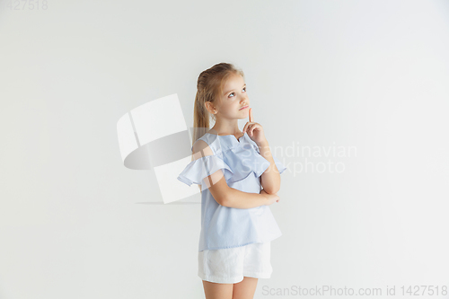 Image of Little smiling girl posing in casual clothes on white studio background