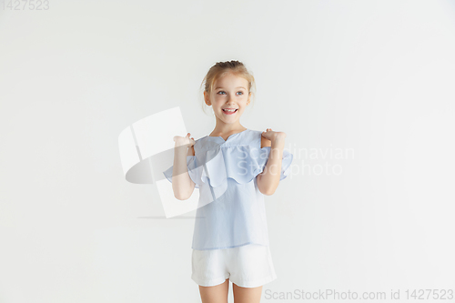 Image of Little smiling girl posing in casual clothes on white studio background