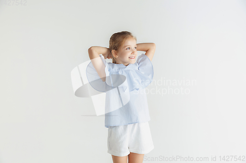 Image of Little smiling girl posing in casual clothes on white studio background