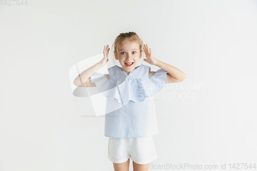 Image of Little smiling girl posing in casual clothes on white studio background