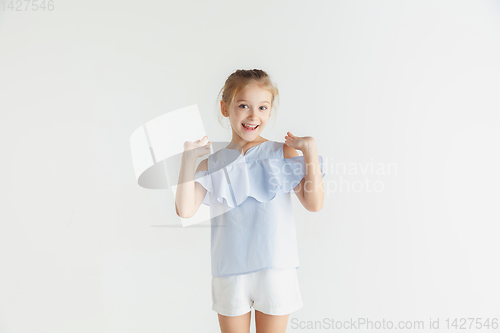 Image of Little smiling girl posing in casual clothes on white studio background