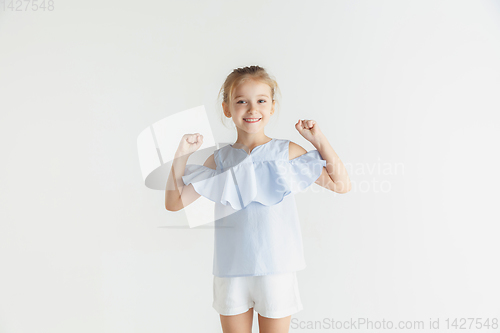 Image of Little smiling girl posing in casual clothes on white studio background